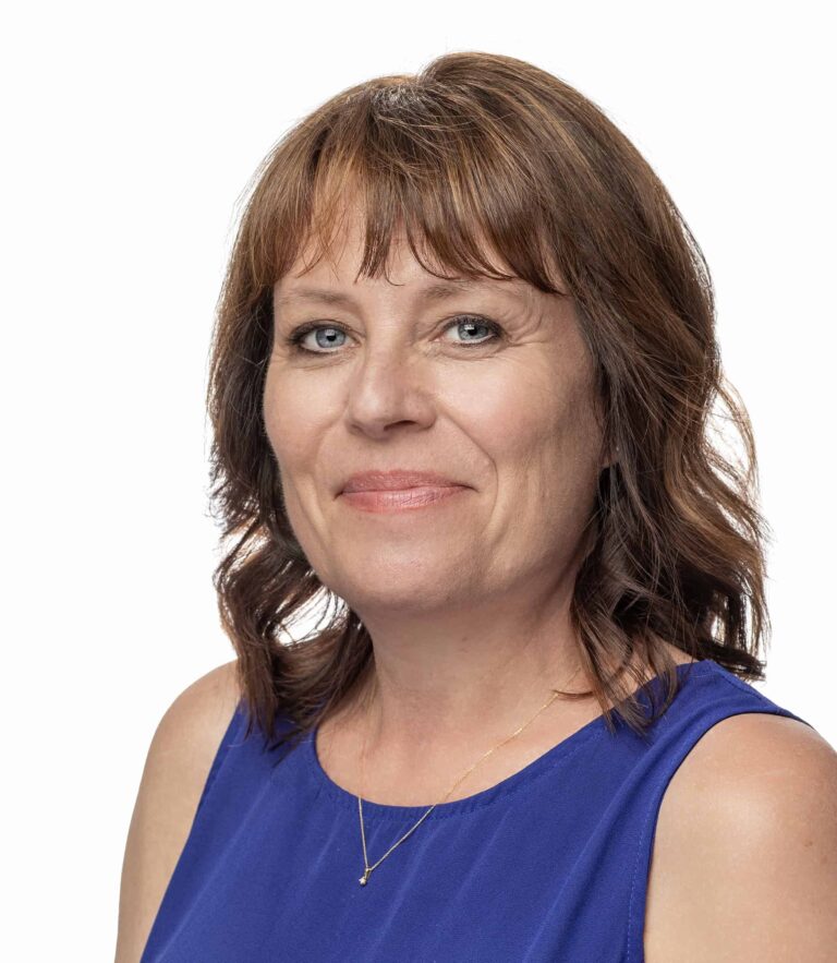 Smiling person with red-brown hair wearing a blue sleeveless top against a white background.