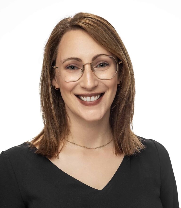Smiling person with glasses wearing a black top against a white background.