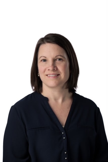 Smiling person wearing a navy blouse against a white background.