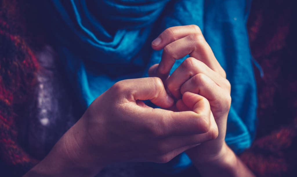 Close-up of hands with fingers touching against blue clothing.